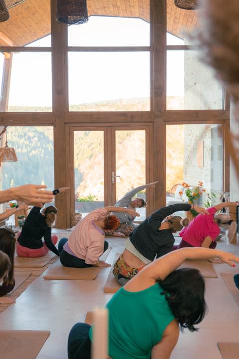 Yogagruppe an der Fensterfront mit Blick ins Tal