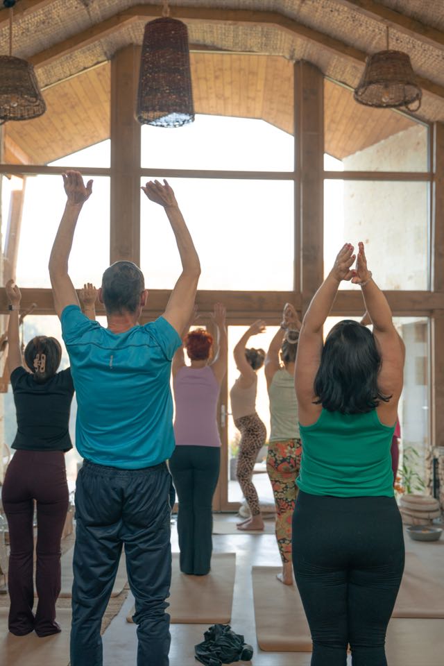 Yogagruppe streckt gemeinsam die Arme nach oben